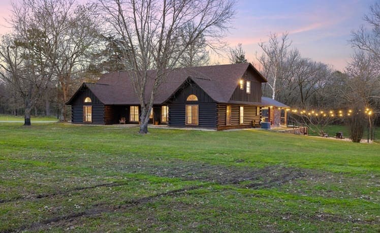 Cabin exterior at night with fire pit and string lights