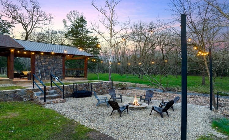 Fire pit seating area with string lights and firewood rack
