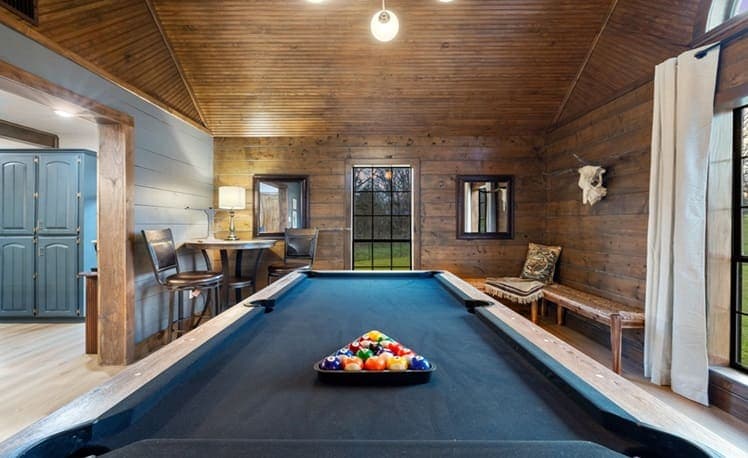 Pool table with warm wood walls in the game room