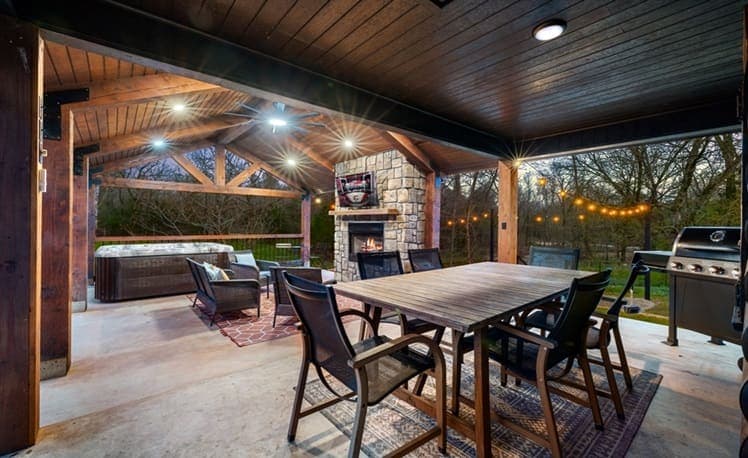 Covered porch dining table with outdoor fireplace and seating